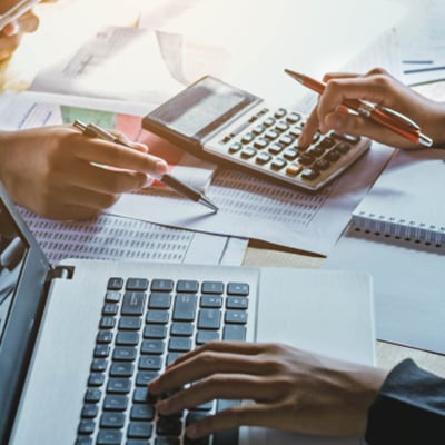 people at desk using computer and calculator