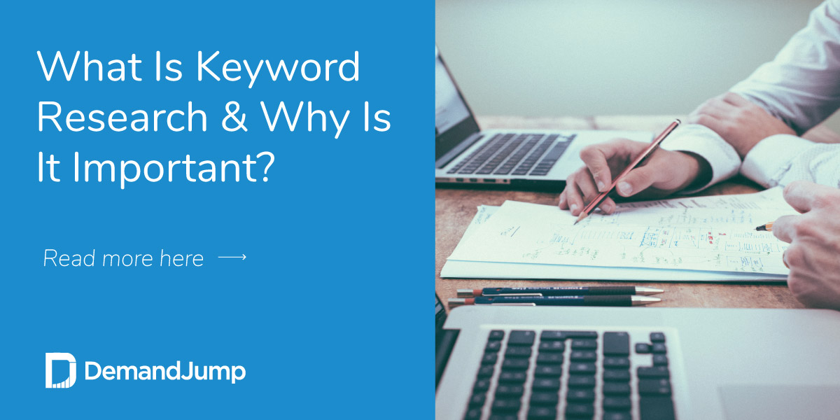 person doing keyword research with paper and pencil sitting near two laptops