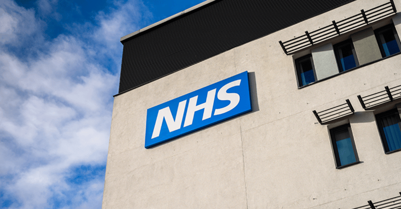 image shows a grey building with the blue NHS logo on it