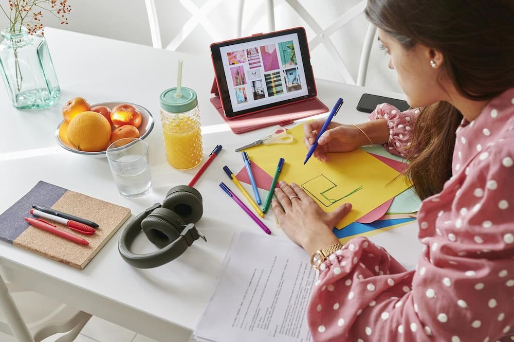 A small business website designer at a desk setting page layouts on a tablet