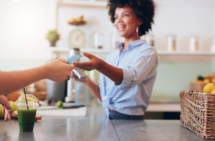 Female small business owner accepting payment from a customer for a smoothie drink
