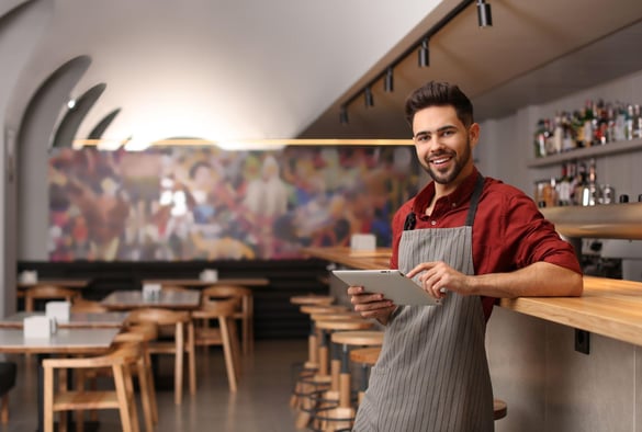 Young male business owner with tablet near counter in his cafe.