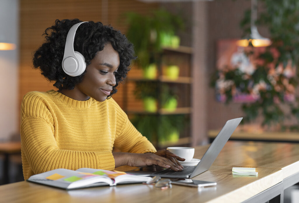 Young woman having online training, using laptop and wireless headset