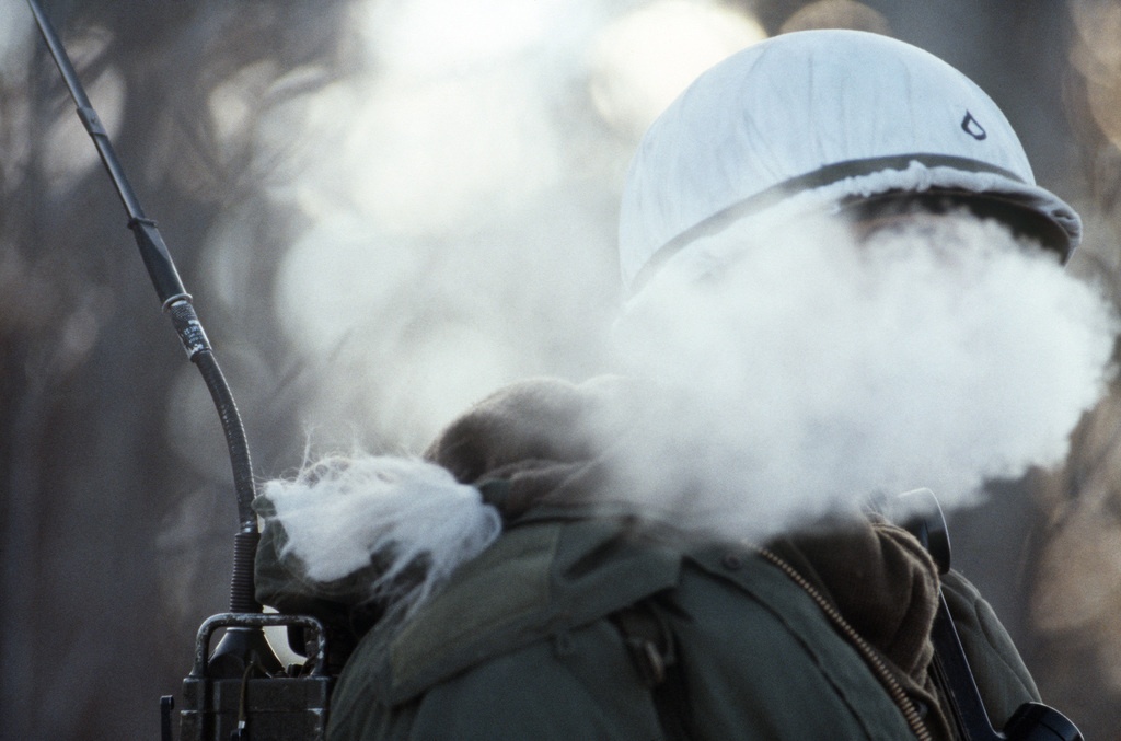A radio operator's breath mixes with the cold Alaskan air to form a steam cloud temporarily shielding his face during Exercise BRIM FROST'87