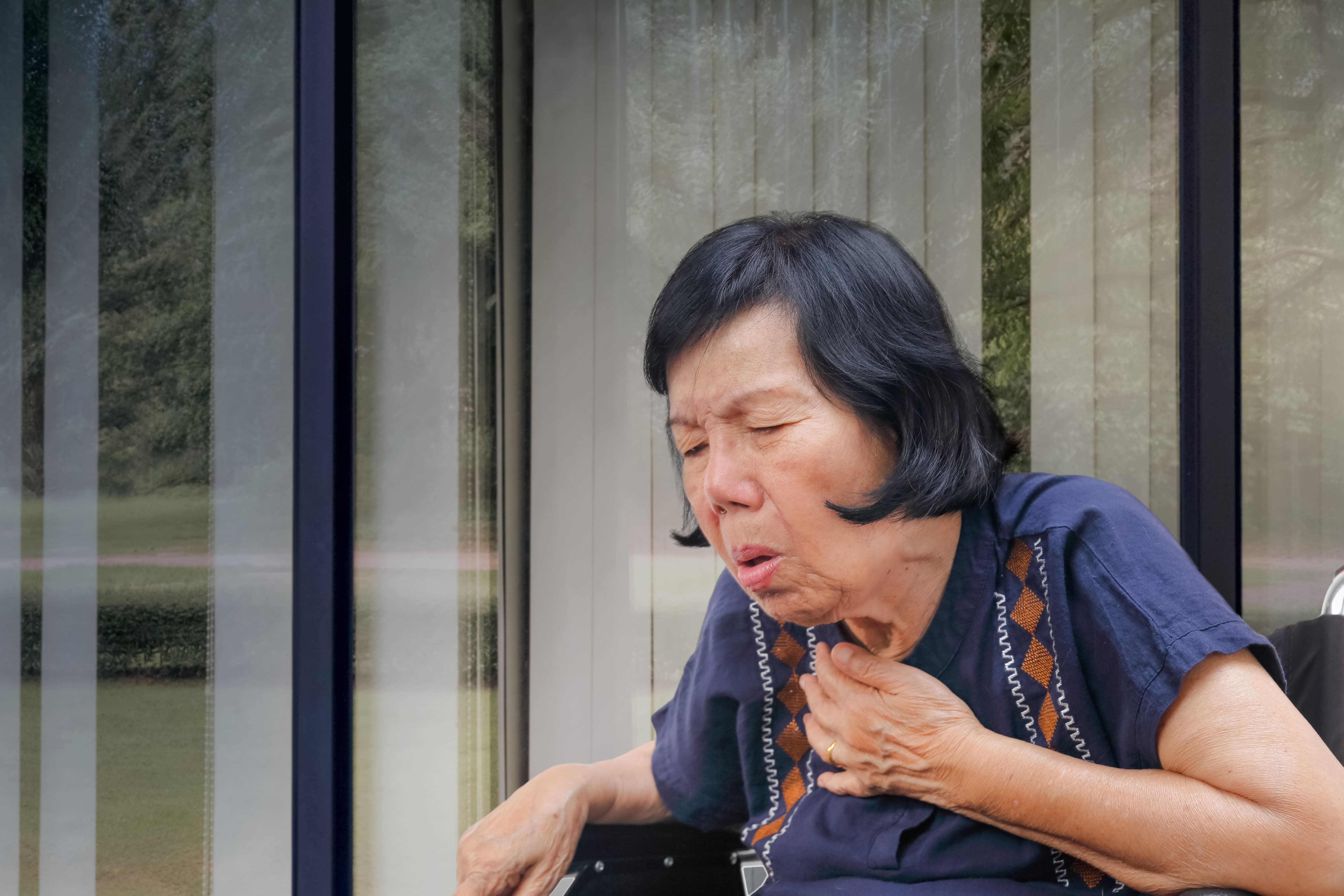 Woman coughing with hand on chest.