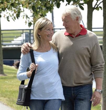 Man and woman walking with portable oxygen concentrator.