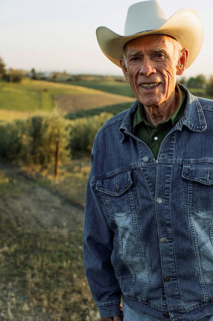 HISPANIC FARMER STANDING IN VINEYARD