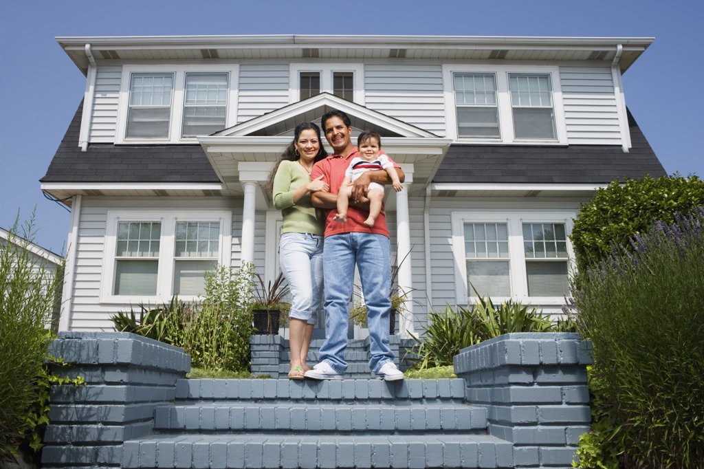 HISPANIC FAMILY STANDING ON STEPS IN FRONT OF HOUSE