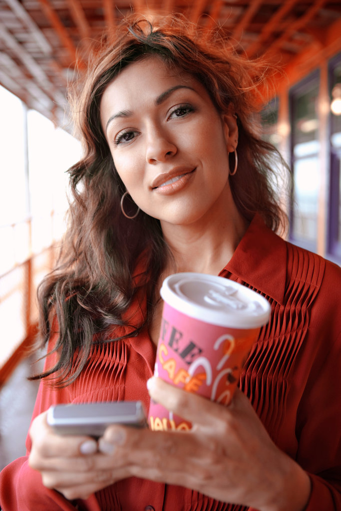 HISPANIC BUSINESSWOMAN HOLDING COFFEE AND CELL PHONE