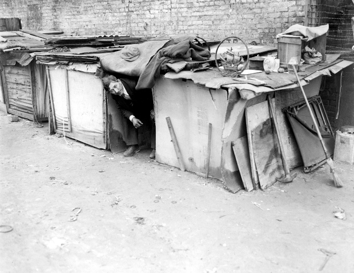 AN UNEMPLOYED MAN LIVING IN A SHACK CONSTRUCTED FROM PACKING CASES AND PIECES OF WOOD IN NEW YORK CITY