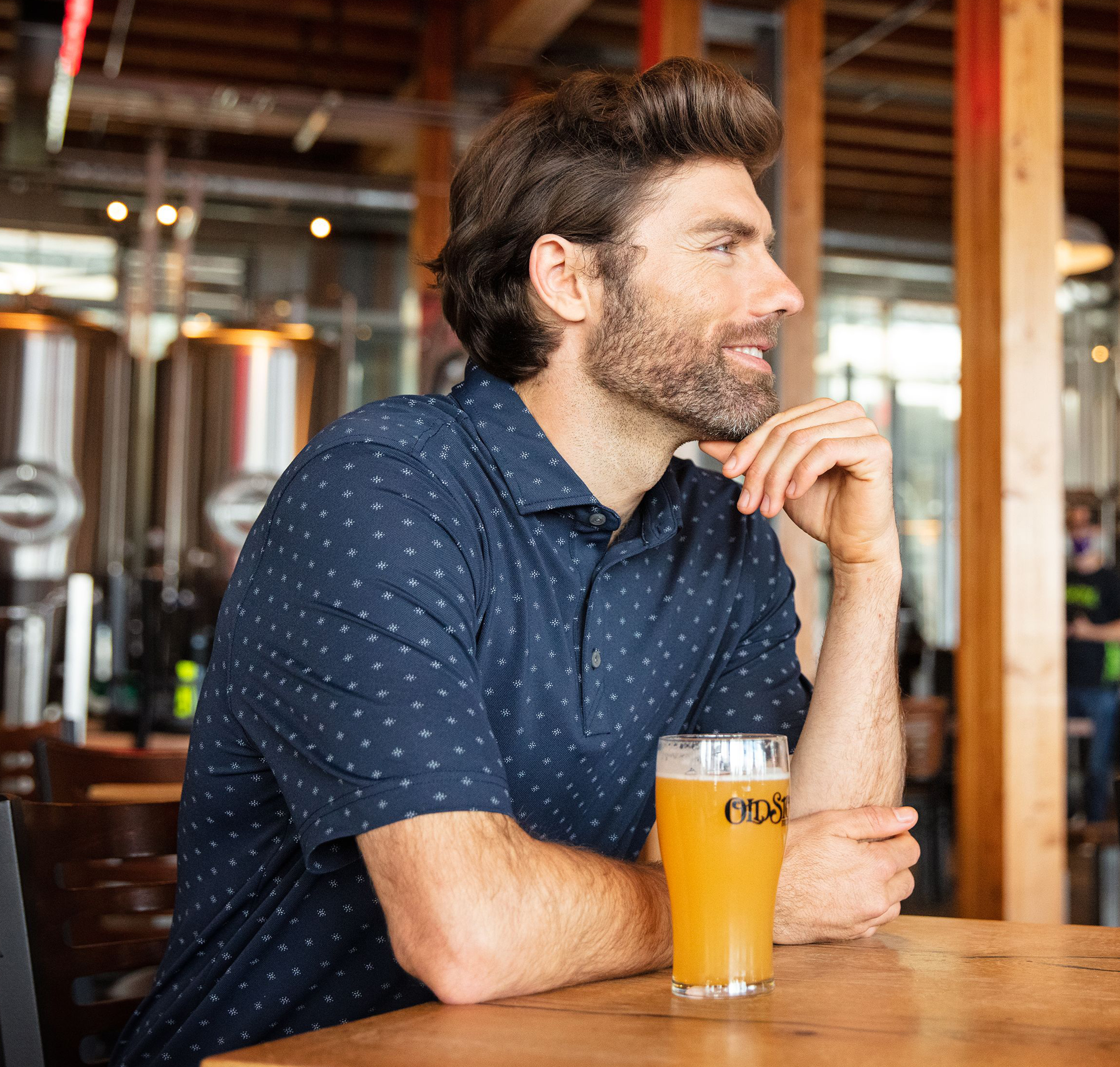 Man wearing a Cutter & Buck Polo and drinking a beer at a brewery