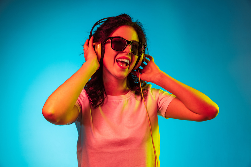 happy-young-woman-listening-music-smiling-trendy-blue-neon-studio