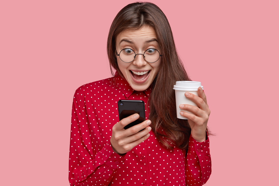 photo-cheerful-young-woman-checks-social-networks-plays-games-phone-browses-online-apps-drinks-takeaway-coffee-dressed-red-clothes (1)