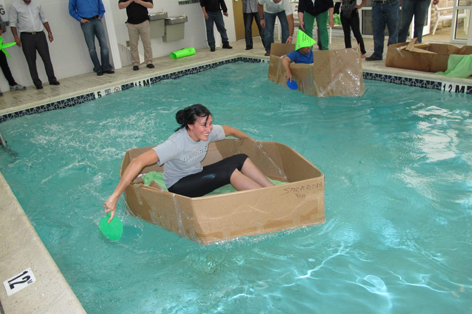 people getting out to a rec center and building carboard boats as a team building activity in the winter 