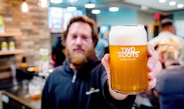 Cannabiniers owner showing off their line of cannabis-infused beer.