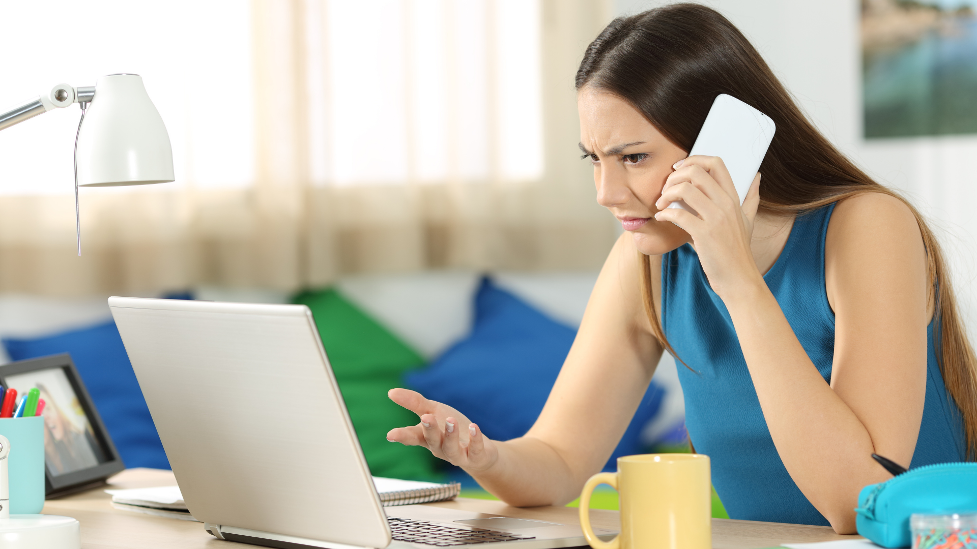 Customer on a cellphone looking angrily at her computer