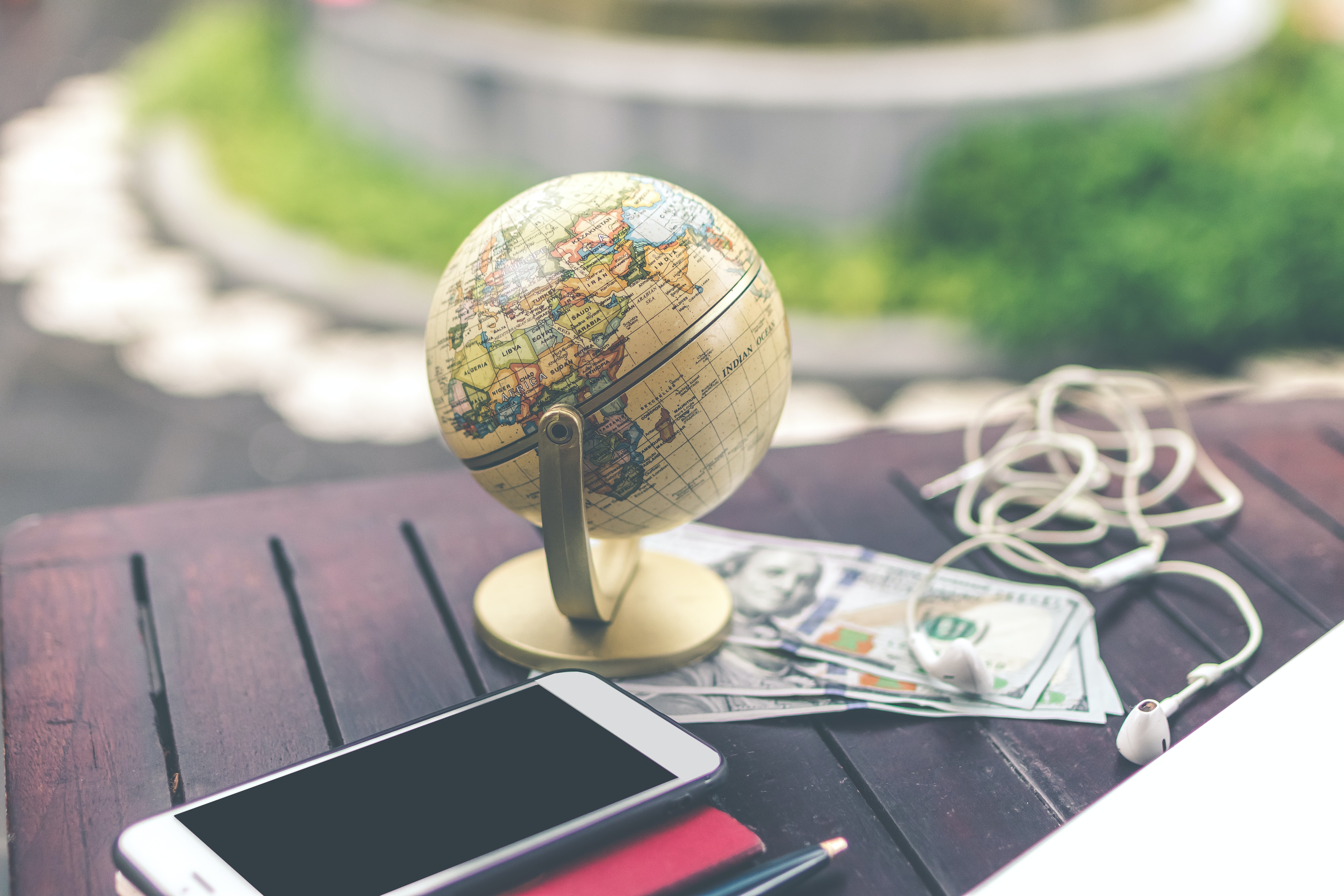 Image of a globe with a stack of multiple paper currencies underneath