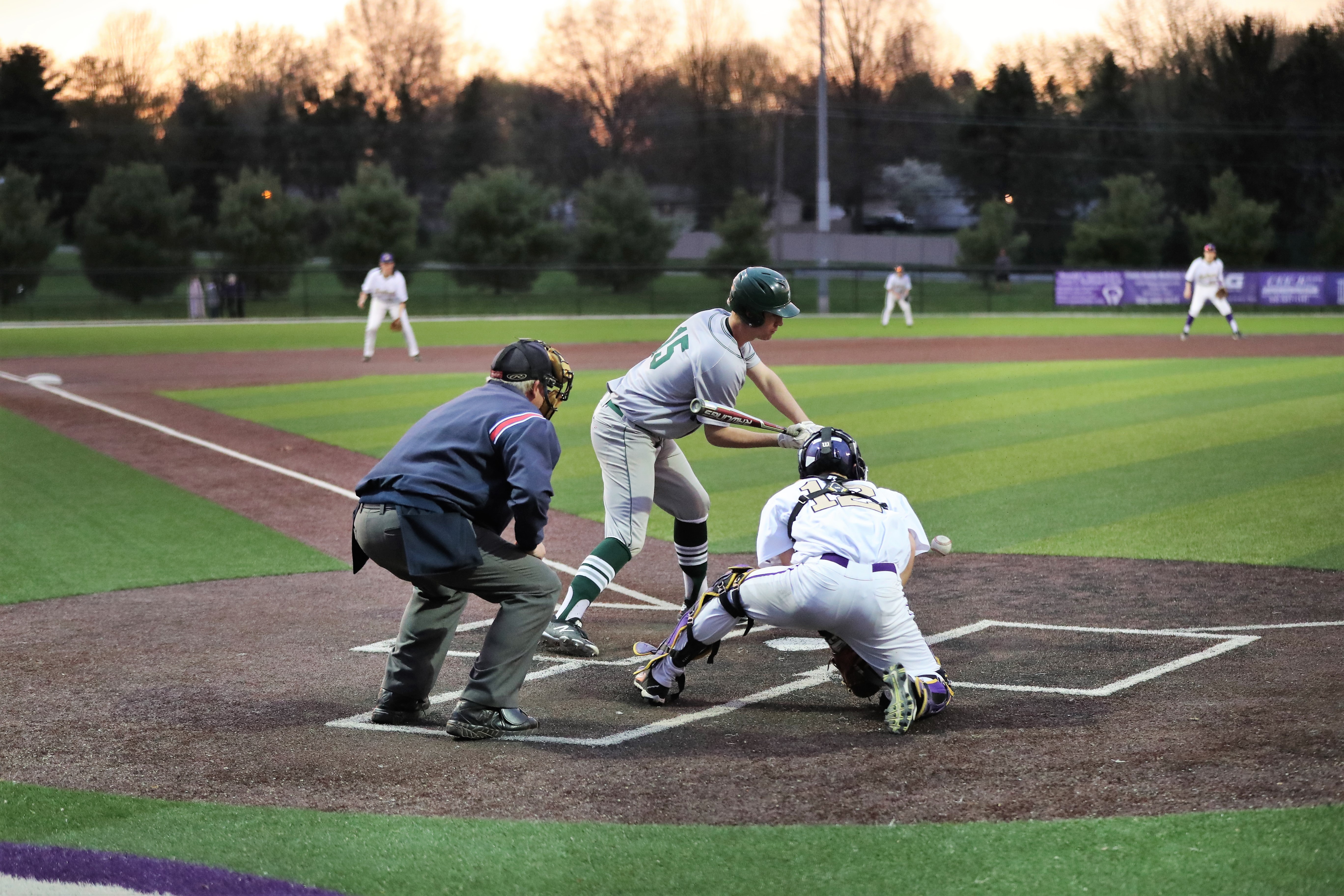 Image of a baseball game at home plate. The player is swinging the bat but it appears the he is missing the ball.