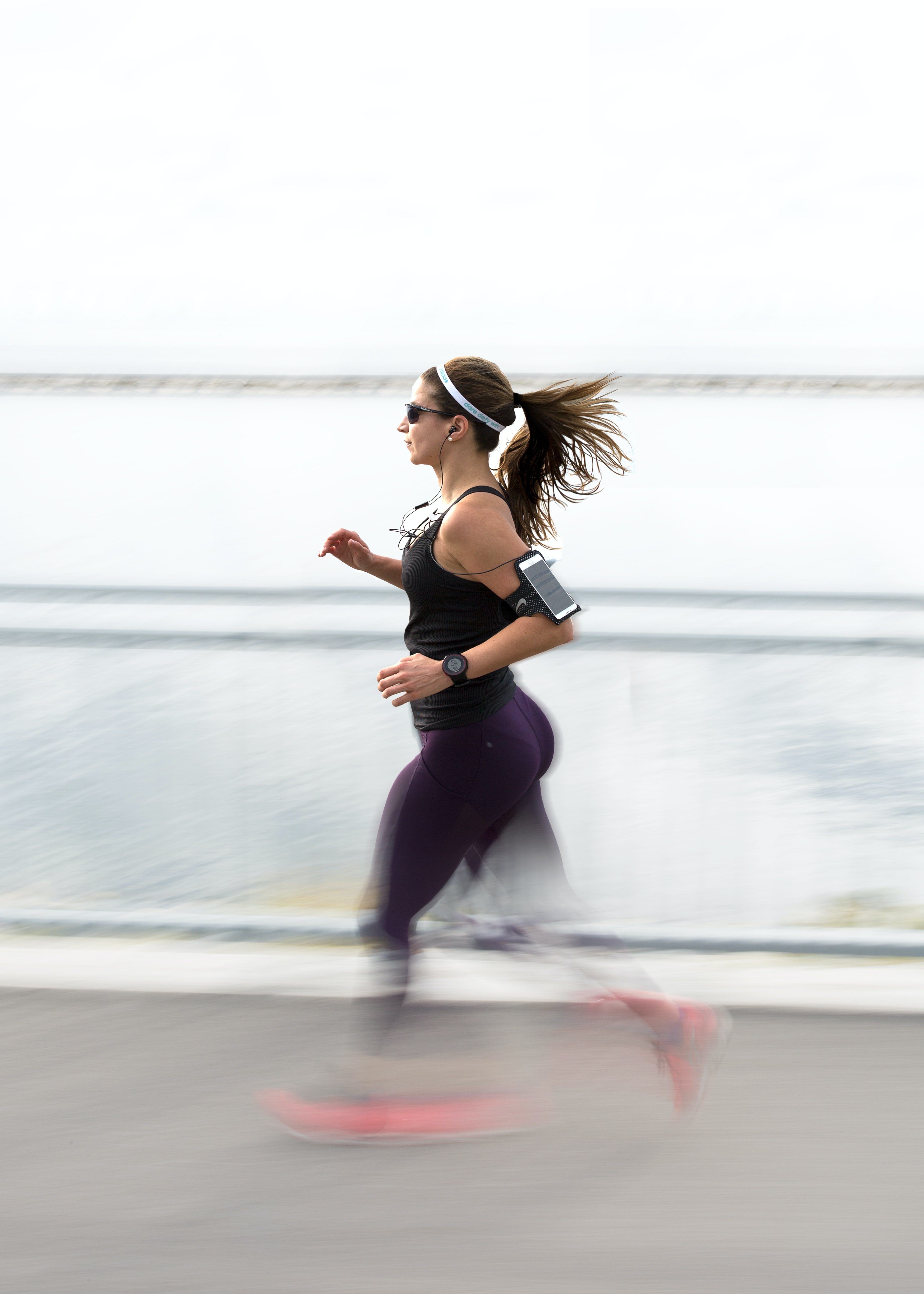 Image of a woman running along a concrete path next to a body of water