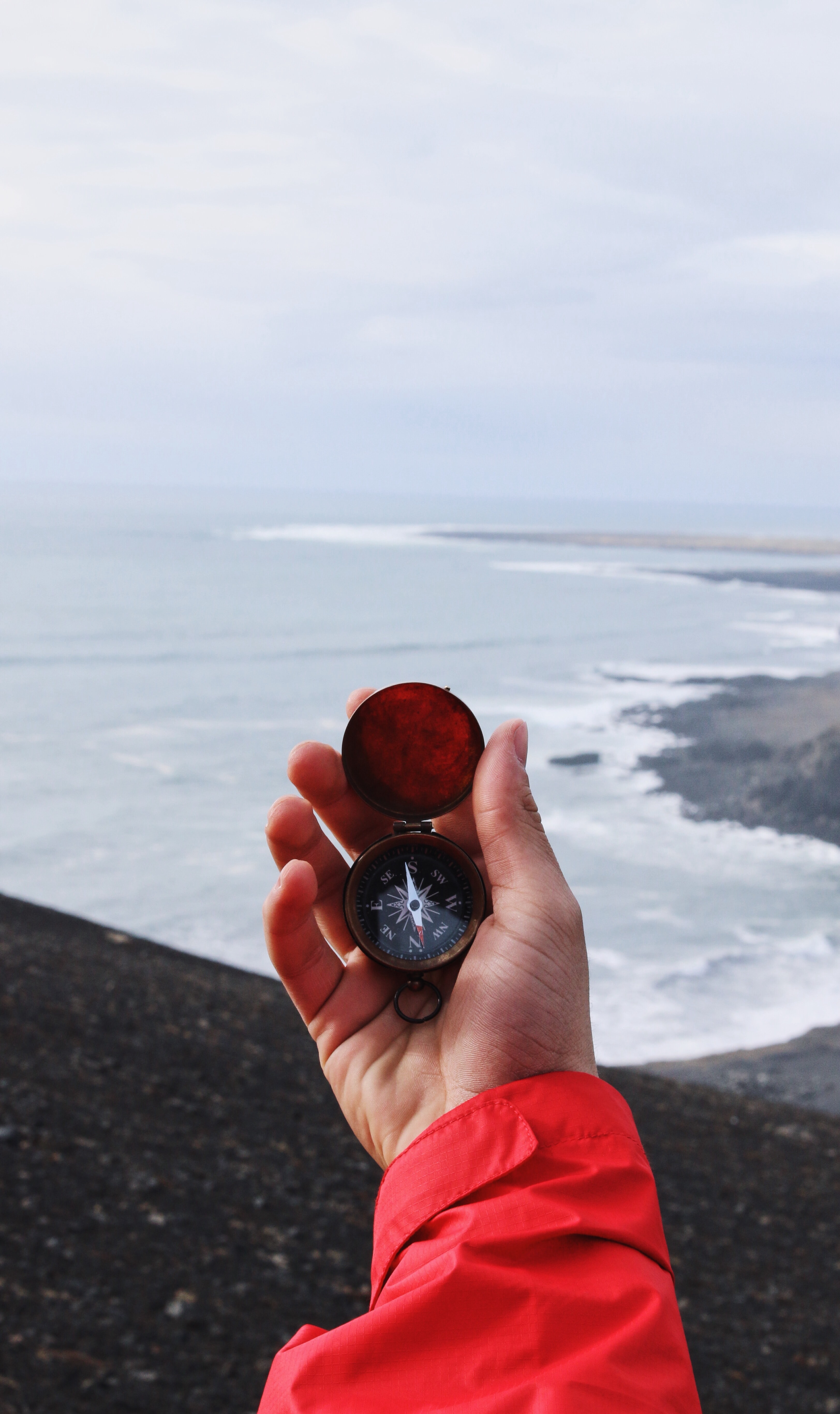 Image of a hand holding a compass in front of a large body of water