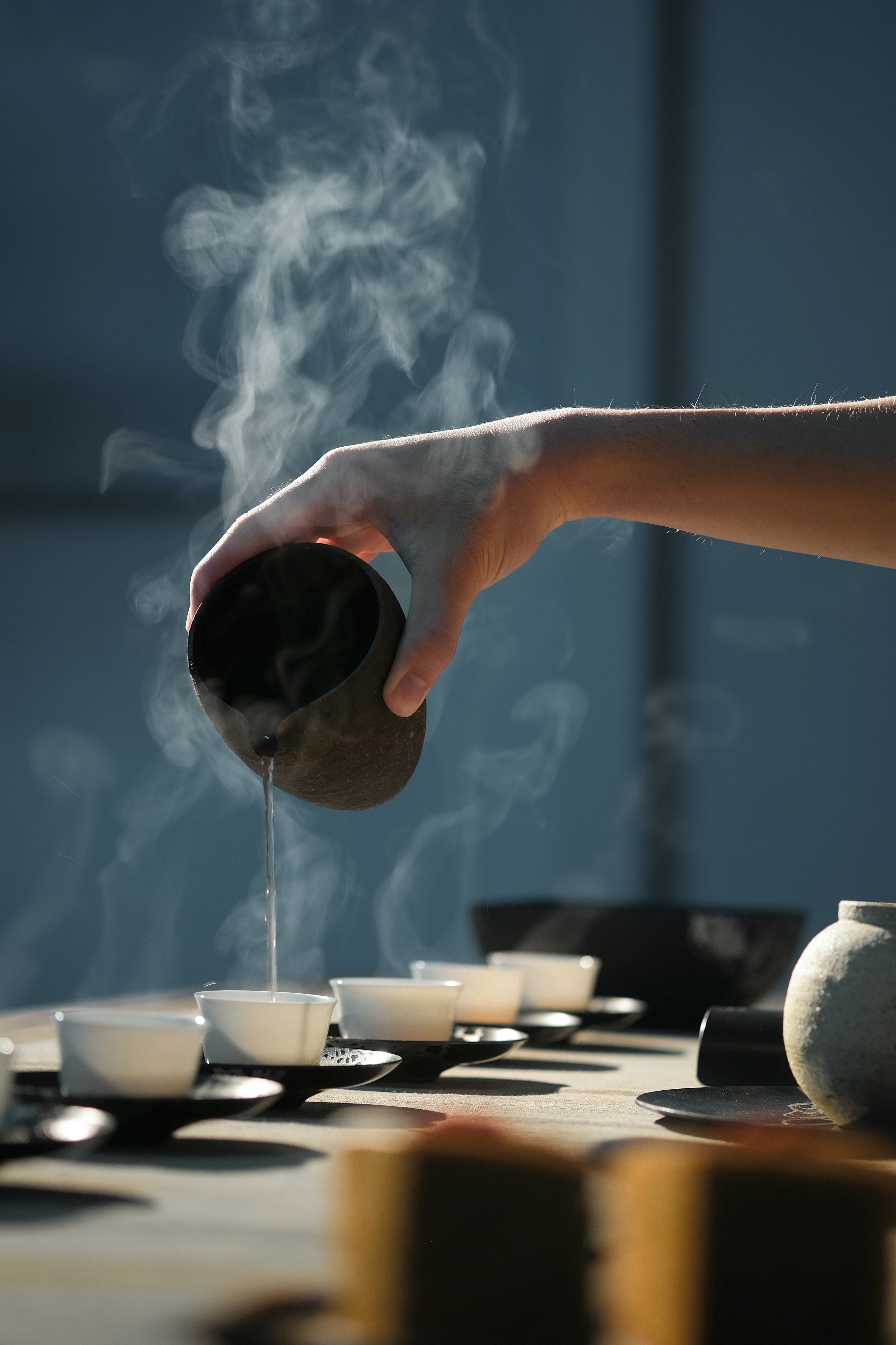 A Chinese tea ceremony with white cups and black saucers.