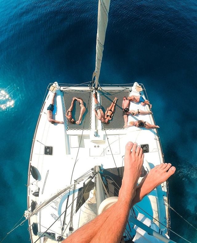 Picture of feet from above a sailboat with people laying on the deck 