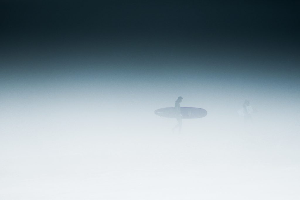 A surfer walking on a misty day in Canada's surf capital of Tofino