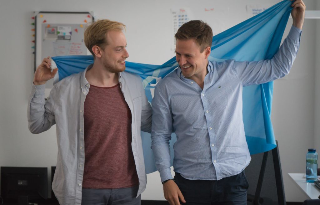 Die Gründer von JoinMyTrip, Niels und Valle, halten die JoinMyTrip Flagge hinter ihrem Rücken.
