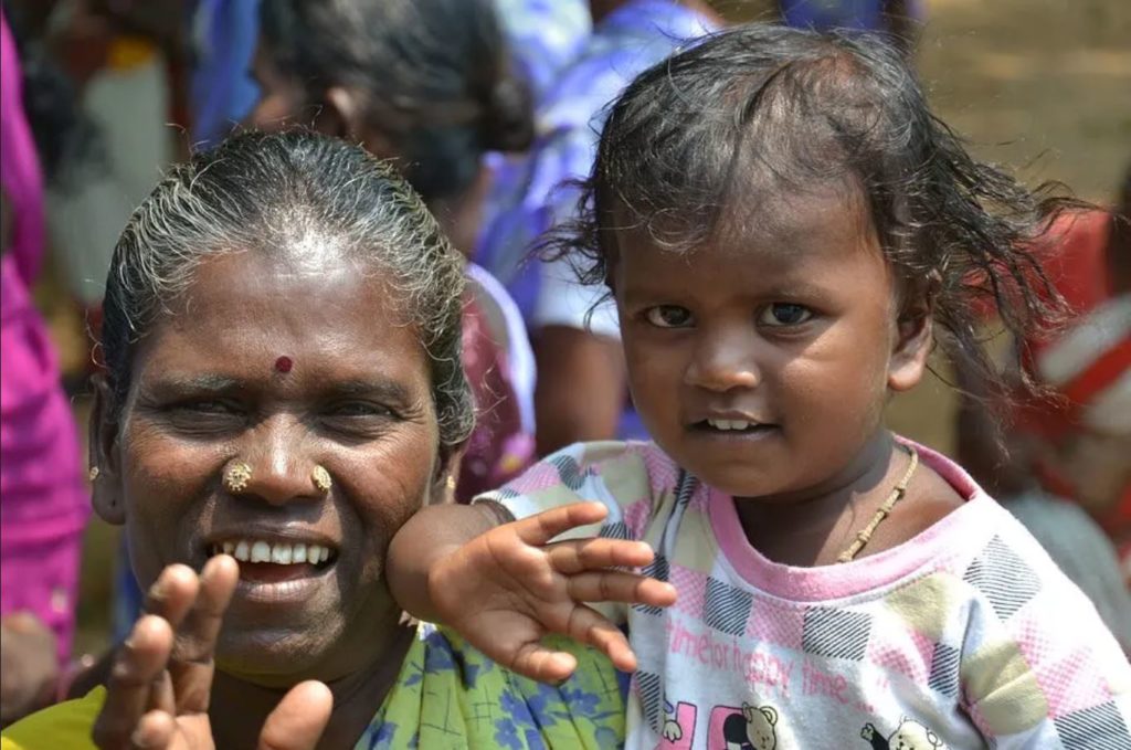 Indian woman with child smiling and waving