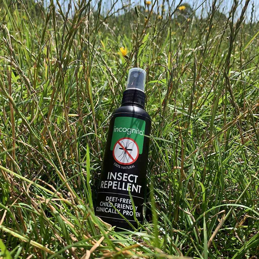 Insect repellent spray bottle laid against the green grass.