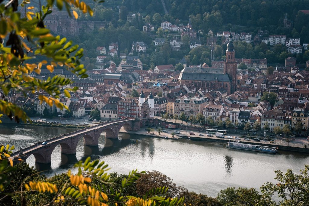 a picture of the city Heidelberg with buildings and a bridge leading over a river