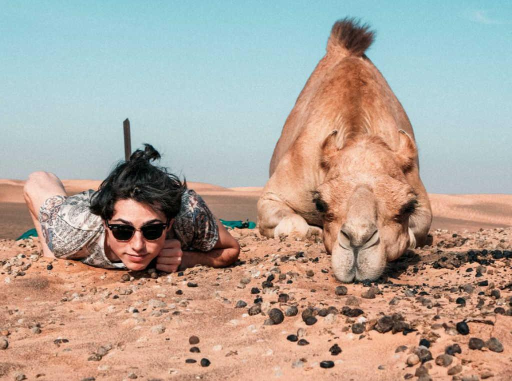 A camel and a group member on a trip having fun together.