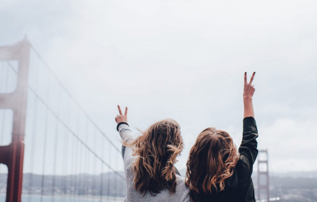 2 women standing in front of the Golden Gate bridge in San Fransisco with their backs to the camera, happy because they found the perfect travel partner.