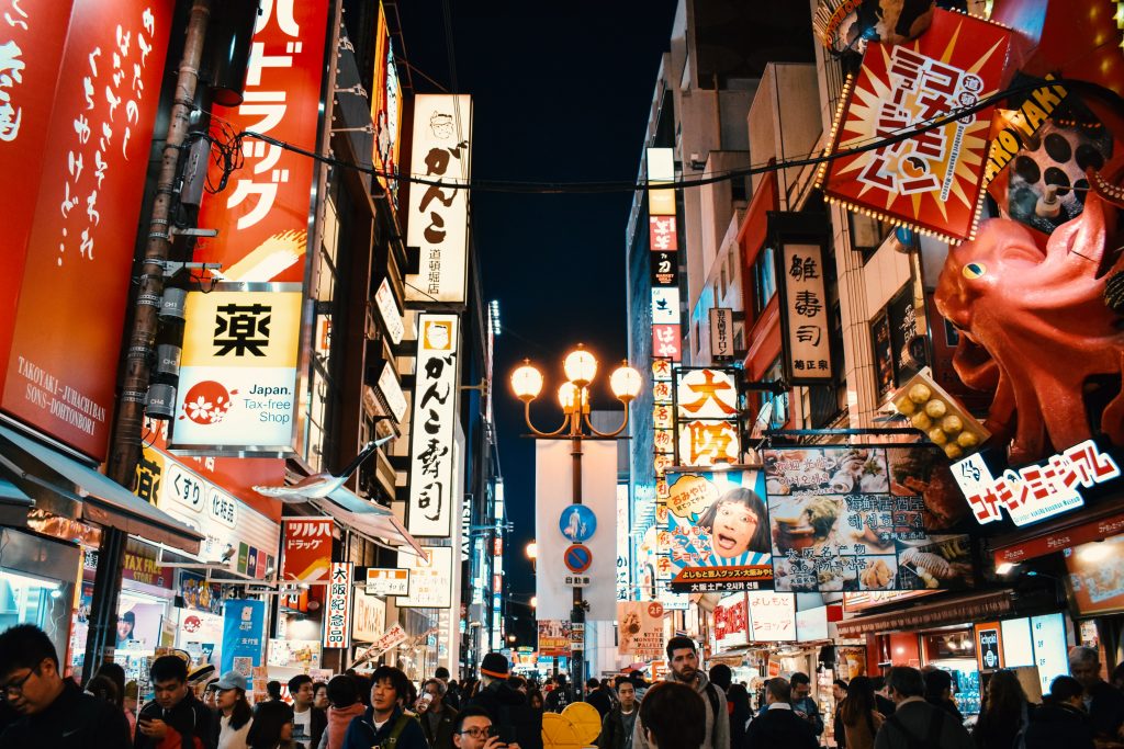 Osaka during the night with people packed in the streets in a Japan travel itinerary.