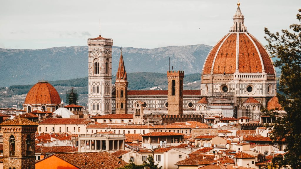 Florence, an old city in Italy, with mountains in the background and a basilica in the middle