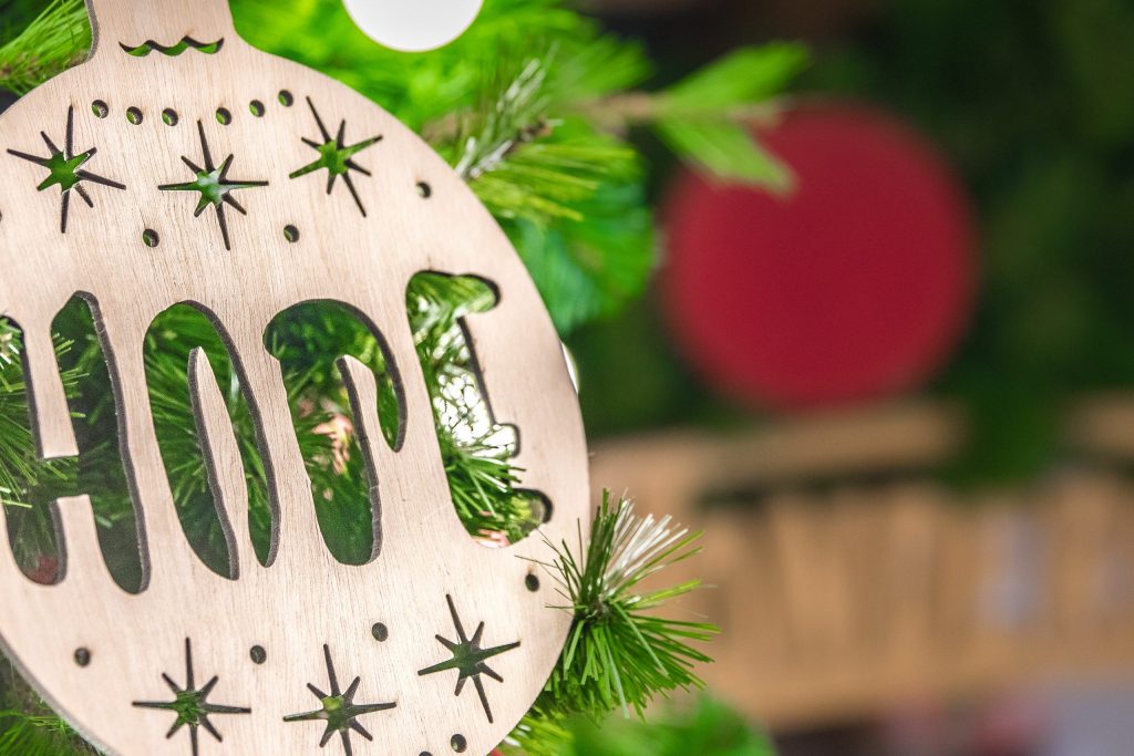 Stay safe this holiday: a christmas bauble made out of wood with the word hope on it 