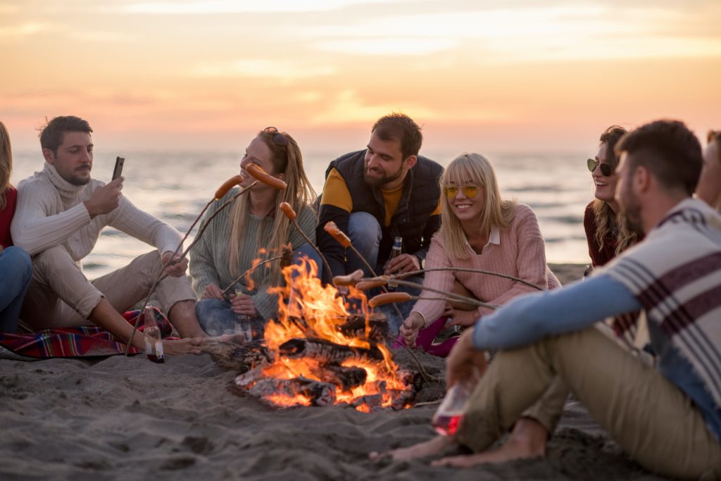 how to be the perfect trip leader people - people sat on the beach around the bonfire 