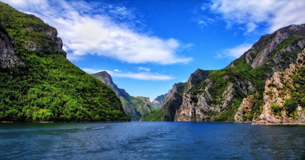 Einzigartige Reiseziele Für Deinen Sommer 2020: Der Koman-Stausee in Albanien mit seinem blauen Wasser umgeben von Felsen