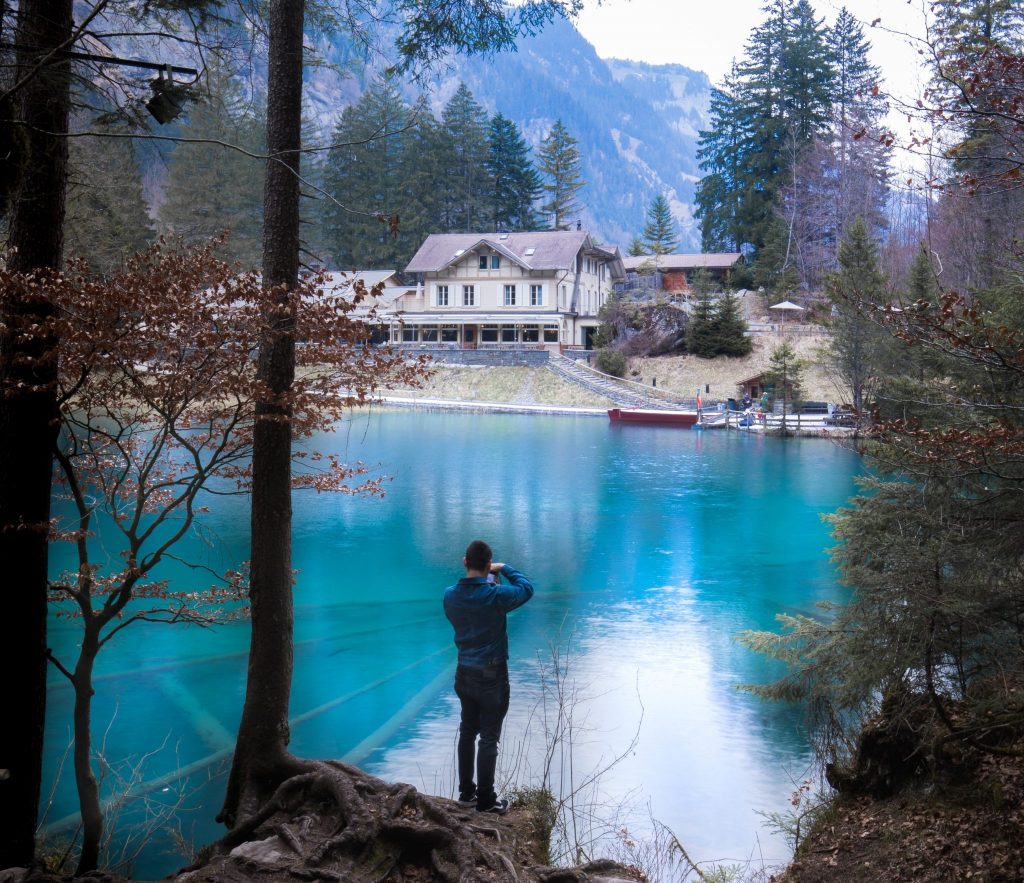 A man takes photos of the blue lake, which is turquoise blue and crystal clear. 