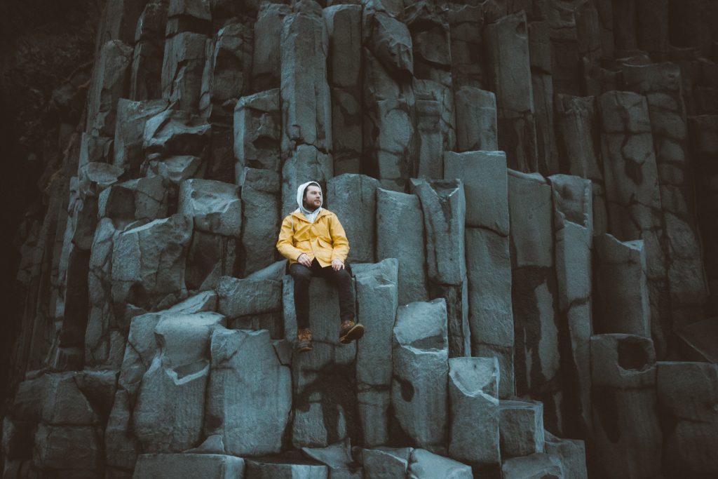 Black rock pillars on a beach in Iceland with man sitting on them