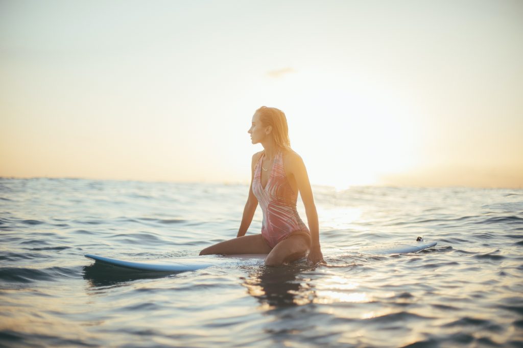 Meaningful lessons learned from traveling is to take things as they come with a girl sitting on her surfboard in the water.