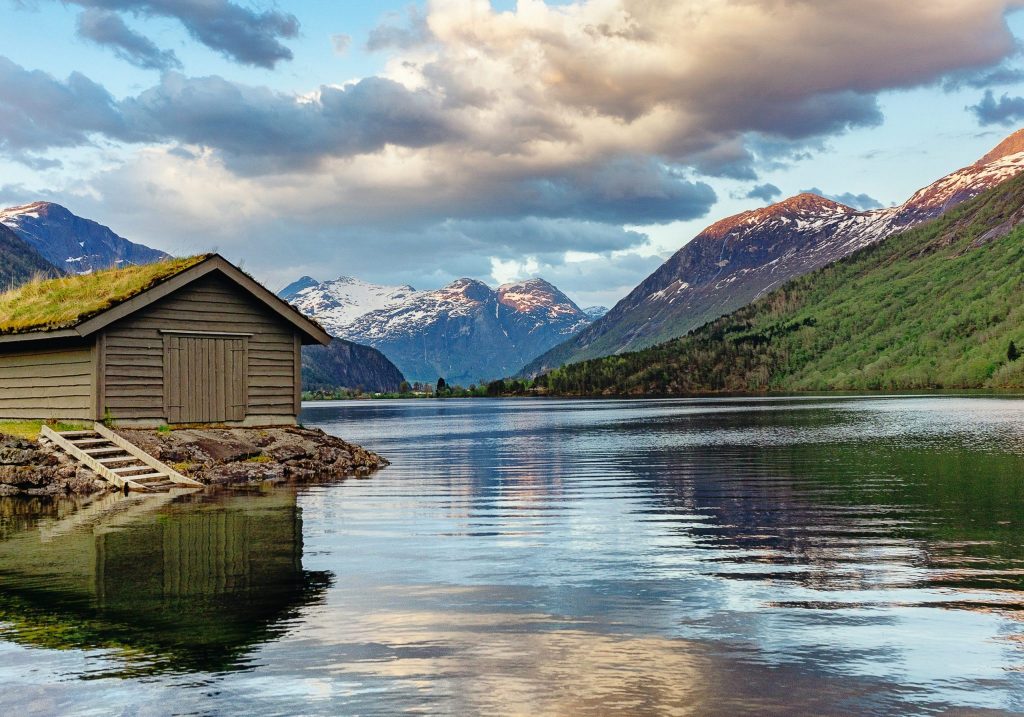 The wide view of a fjord in Norway with a small wooden hut in the foreground.