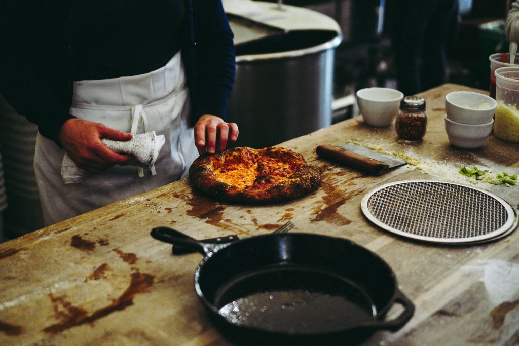 Insider tips for Amsterdam with a pizza and pan on top of a wooden counter.