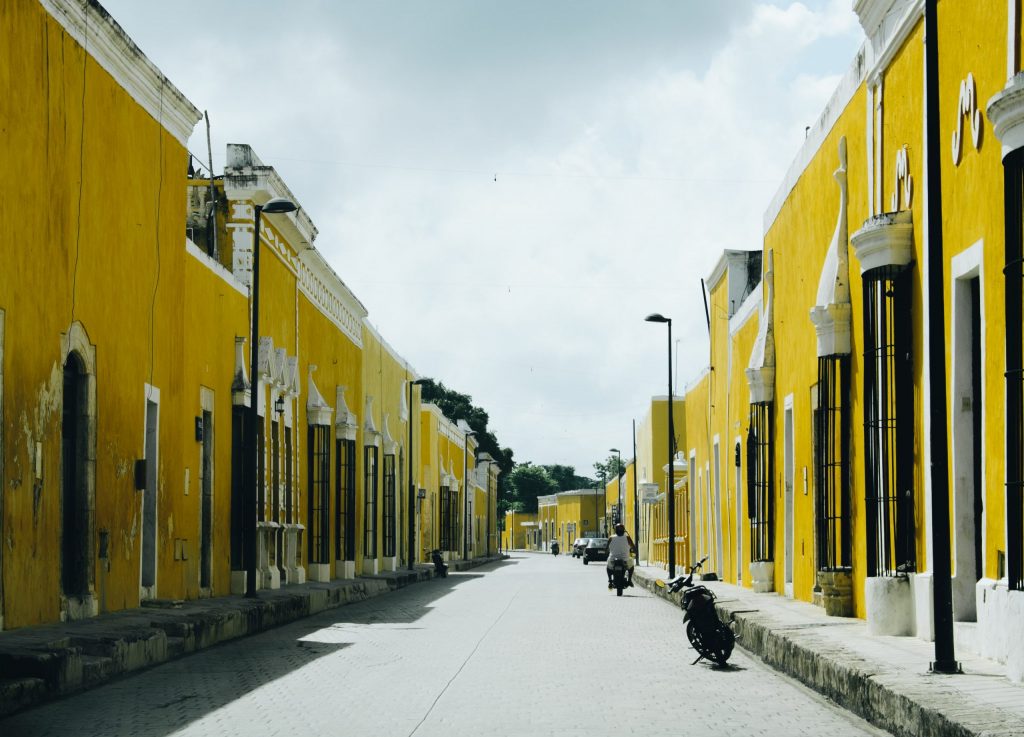 The yellow city in Mexico. Yellow houses lining the street and someone driving a motorbike in the distance