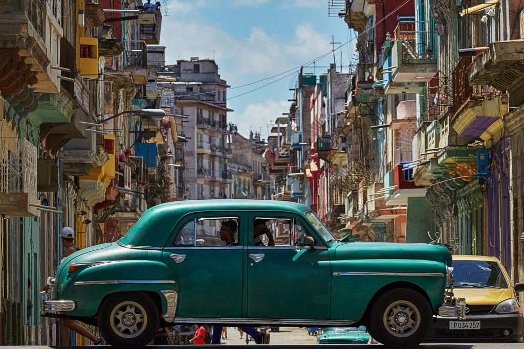Lively streets of Havana in Cuba with old cars and colorful houses.