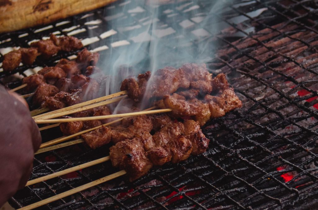 Insider tip is to try out Bali street food with meat on a stick frying.