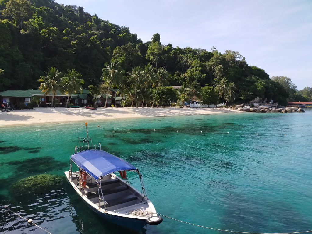 Perhentian Islands in Malaysia with turquoise blue waters and a boat.