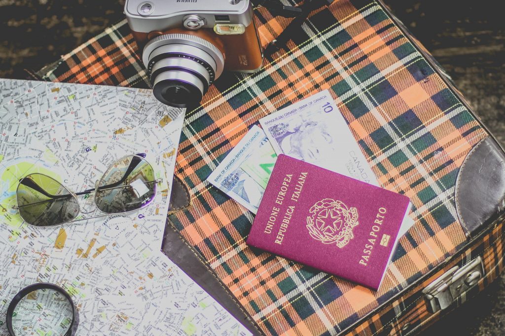 Reisepass mit Kamera und Straßenkarten auf einer karierten Decke.