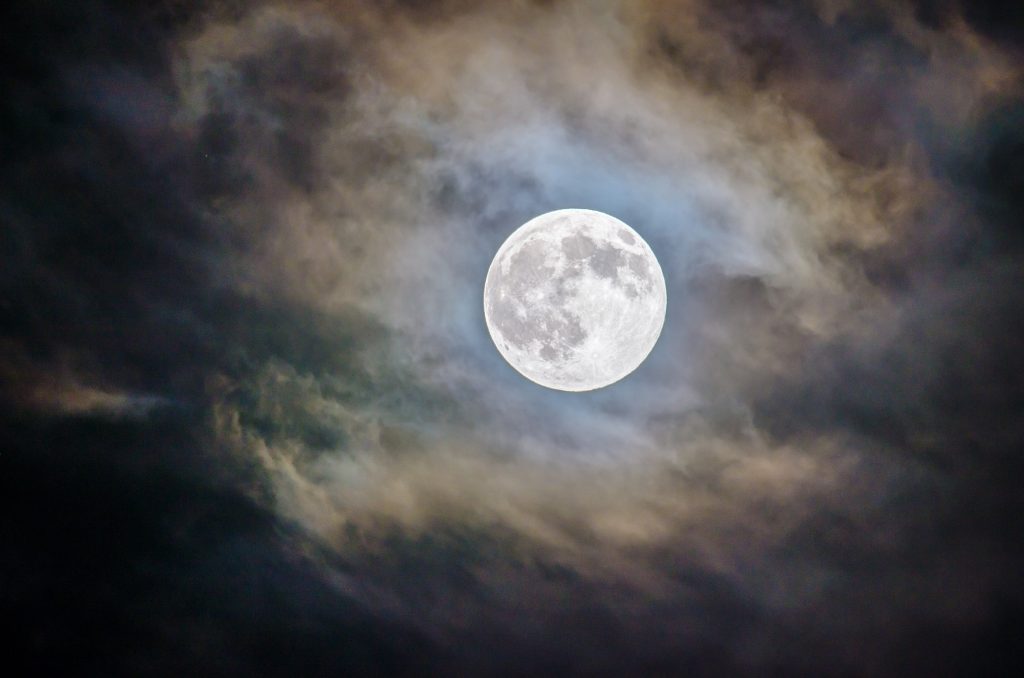 The moon in a cloudy night sky, where Neil Armstrong once landed