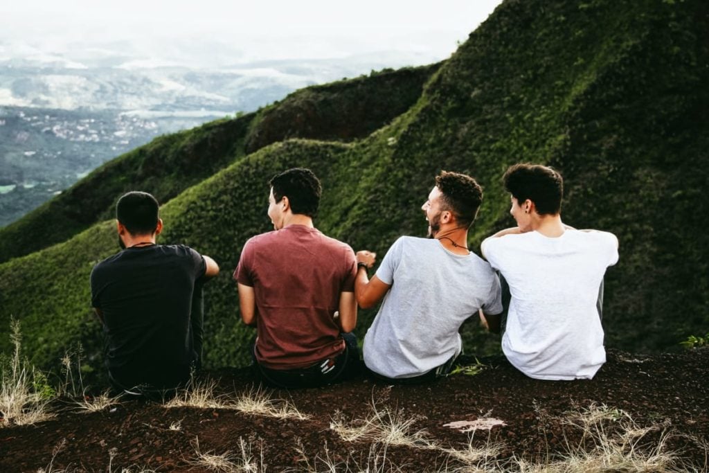 a group of guys sat on a hill laughing together